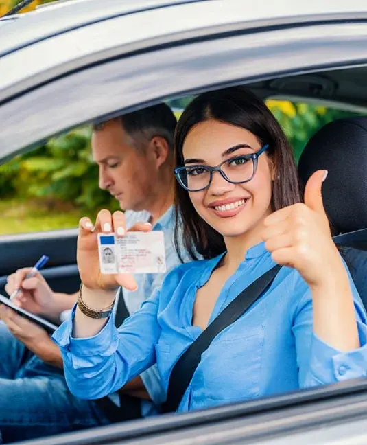 a person in a car holding up a driver's license